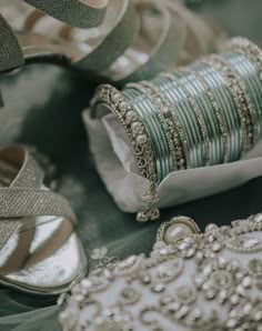 several different types of bracelets and shoes sitting on top of a cloth covered table