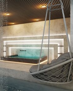 an indoor swimming pool with a swing chair and hot tub in the middle, surrounded by concrete walls