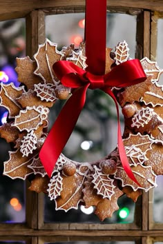 a christmas wreath made out of gingerbreads hanging from a wooden frame with a red ribbon