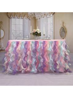 a table covered in pink, blue and purple ruffles with candles on it