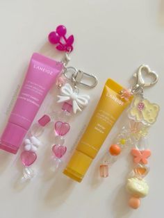 three different types of personal care items on a white surface with keychains attached to them