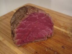 a piece of meat sitting on top of a wooden cutting board