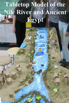 two girls standing in front of a table made out of sand and paper machs