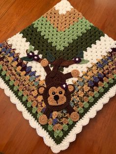 a crocheted blanket with a monkey on it sitting on the floor next to a wooden table