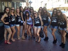 a group of young women standing next to each other on a brick sidewalk in front of a building