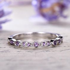 a white gold ring with pink sapphires and diamonds on the side, sitting on a table