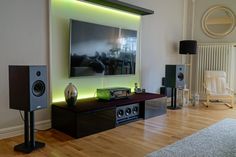 an entertainment center with speakers and a large screen television on the wall in a living room