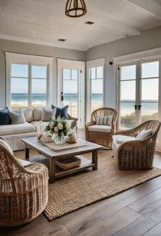 a living room with wicker furniture and large windows looking out to the beach in the distance