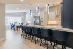 a kitchen with an island and bar stools next to the dining room table in front of it