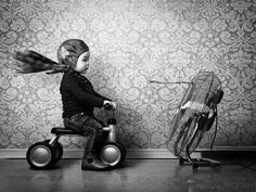 a little boy sitting on top of a small tricycle next to a bird cage