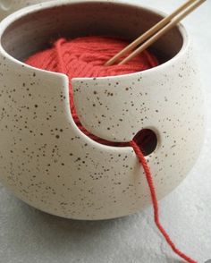 a bowl with yarn in it and two knitting needles sticking out of the top one