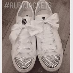 a pair of white tennis shoes with bows on them