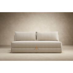 a white couch sitting on top of a floor next to a wall with two pillows