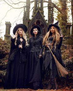 three women dressed as witches standing in front of a building