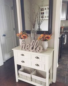 there is a white dresser with two vases on it and flowers in front of the mirror