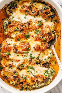 a casserole dish with cheese and spinach in it on a marble surface