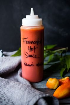 a hot sauce bottle with writing on it next to sliced peaches and green leaves