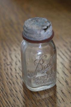 a glass jar with a metal lid sitting on a wooden table