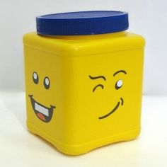 a yellow plastic container with a blue lid and smiling face on it's side