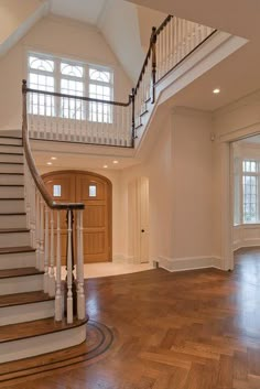 an empty foyer with wooden floors and white railings