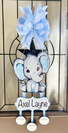 an elephant with a blue bow hanging from it's head in front of a glass door