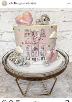 a pink and white cake sitting on top of a metal stand next to a brick wall