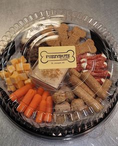 an assortment of meats, cheese and vegetables in a clear plastic tray on a table