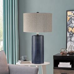 a living room with blue walls and a lamp on a table next to a chair