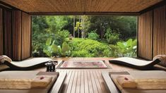 the inside of a spa room with wooden floors and large windows looking out onto trees