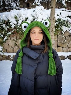 a woman wearing a green frog hat in the snow