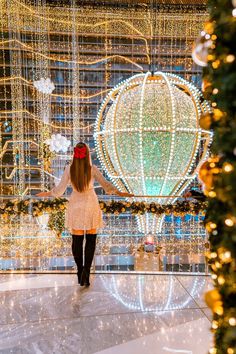 a woman walking in front of a christmas display with lights and decorations on the walls