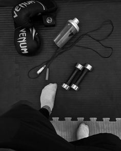 a man sitting on the ground with his feet propped up next to some batteries and a water bottle