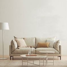 a living room with a couch, coffee table and lamp on the floor in front of it