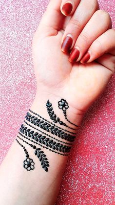 a woman's hand with a black and white tattoo design on it, holding her wrist