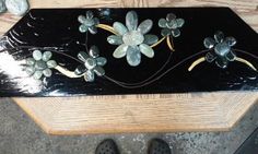 a close up of a wooden box with flowers and leaves on the top, near a pair of black shoes