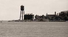 a black and white photo of an island with a water tower in the background