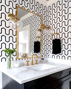 a black and white bathroom with geometric wallpaper