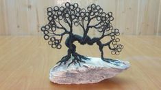 a wire tree sculpture sitting on top of a rock