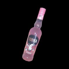 a bottle of vodka sitting on top of a black table next to a pink cap