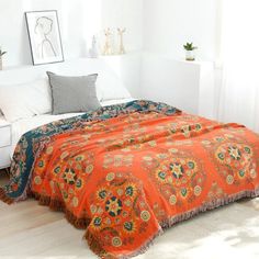 an orange and blue bedspread on a white bed