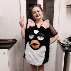 a woman in a black and white cat costume posing for the camera with her hand up