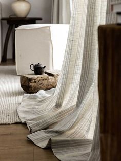 a coffee cup is sitting on a piece of driftwood in front of a curtain