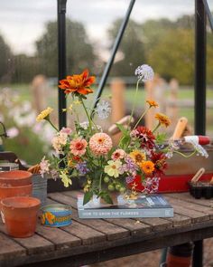 a wooden table topped with lots of flowers next to pots and watering equipment on top of it