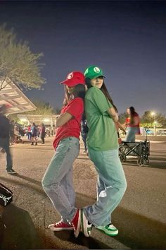 two young people are standing on skateboards in the street at night, one is hugging the other's back