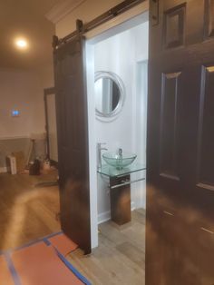 an open door leading to a bathroom with a sink and mirror on the wall next to it