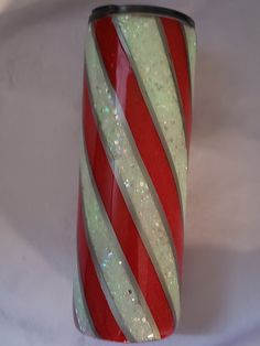 a red and white striped glass vase sitting on top of a white table covered in glitter