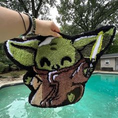 someone holding up a star wars yoda rug in front of a pool