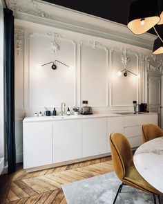 an elegant kitchen with white cabinets and marble counter tops, along with yellow chairs in the center