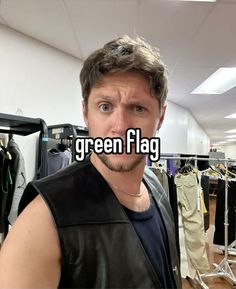 a man is standing in front of clothing racks with the words green flag on it