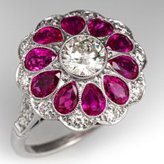 a pink diamond and white gold ring set with rubish cut diamonds, surrounded by round brilliant ruby stones